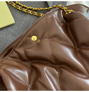 Detail of dark brown quilted leather pattern and gold chain strap on the handbag
