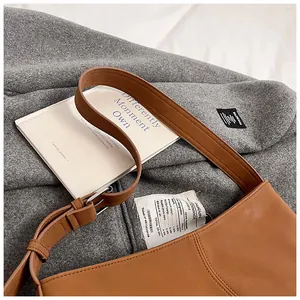 Detail shot of caramel leather tote bag on grey coat with silver metal strap buckle