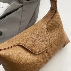 Détail d'un sac sous les bras en cuir marron vintage avec logo embossé et grainé