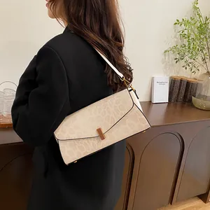 Dettaglio borsa a spalla retrò beige con trama a serpente e fibbia in legno su modella