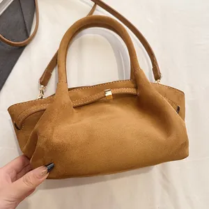 Detail showing the brown suede tote bag with a golden metallic buckle and pleated finish