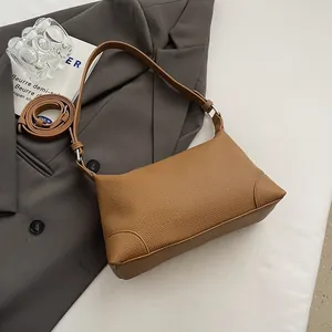 Détail du cuir grainé marron et de la bandoulière amovible du sac baguette rétro