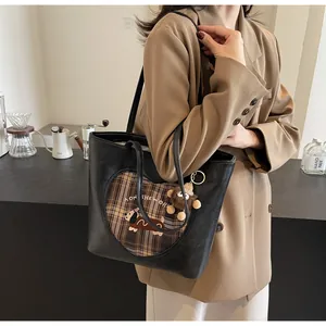Detail einer großen schwarzen Totebag mit Herzmuster und Plüschaffen-Anhänger an der Schulter