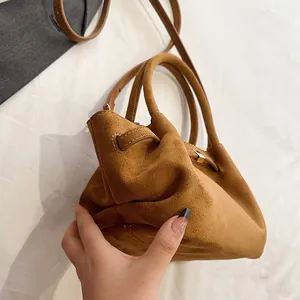 Detail of caramel brown suede tote bag featuring smooth metal clasp and dual handles
