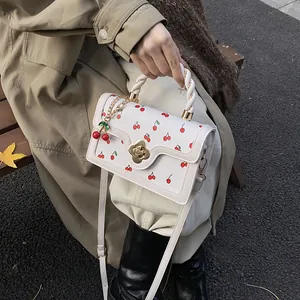 Borsa a tracolla bianca con stampa ciliegie, chiusura a camelia oro e ciondolo
