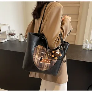 Detail der schwarzen Ledertasche mit Herzausschnitt und süßem Affenanhänger am Riemen