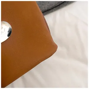 Detail of caramel brown faux leather texture with silver metal rivet on a tote bag