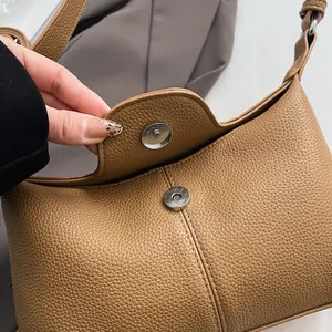 Détail de la boucle magnétique argentée sur le sac bandoulière en cuir marron