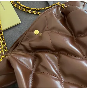 Detailed view of dark brown quilted leather texture with gold chain strap and buckle