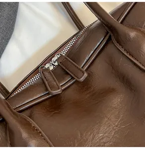 Close-up of premium brown leather texture and silver zipper detail on the tote bag