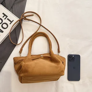 Detail view of brown faux suede tote bag with pleated texture and golden buckle accent