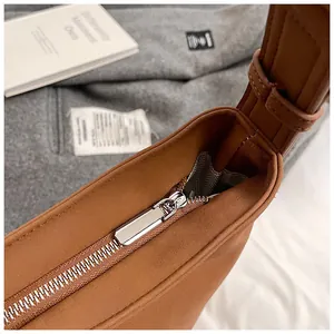 Detailed close-up of silver metal zipper closure and brown leather texture on tote bag