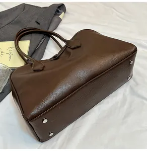 Detailed view of silver metal base studs on dark brown textured leather tote bag