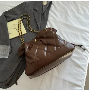 Detailed view of brown quilted bucket bag with gold chain strap on white fabric