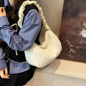 Close-up of beige quilted cloud bag with ruched shoulder strap on model for size view
