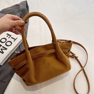 Detail of brown suede tote bag featuring matte texture and circular handles for work