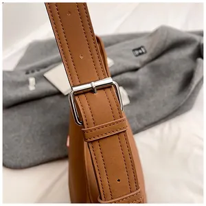 Detail of brown leather strap with lychee texture and polished silver buckle on tote bag