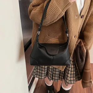 Détail du sac à bandoulière en cuir grainé noir montrant la texture et la sangle