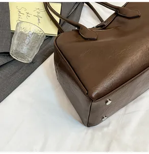 Detailed view of dark brown leather tote bag showing smooth texture and silver bottom studs