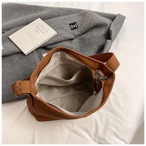 Detailed interior of brown leather tote showing gray fabric lining and zipper pocket