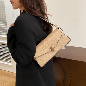 Dettaglio della borsa beige leopardata con chiusura metallica sopra un blazer