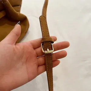 Detailed macro of the adjustable brown suede shoulder strap with a gold metal buckle
