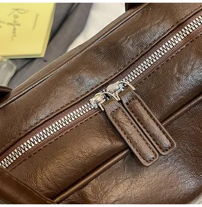 Detail of dual metal zippers and textured dark brown leather on vintage tote bag