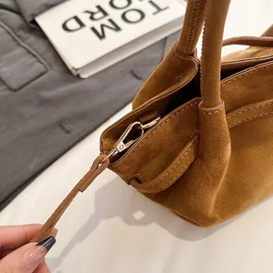 Close-up of golden lobster clasp and stitching on brown suede retro tote bag