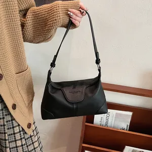 Détail d'un sac porté épaule en cuir noir grainé avec des boucles en métal argenté chic