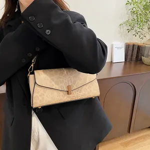 Dettaglio borsa baguette beige effetto pelle di serpente con fibbia rettangolare in bronzo