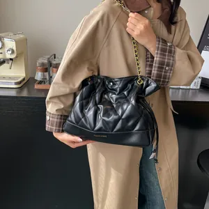 Detail of black quilted bucket bag with gold chain strap and elegant texture