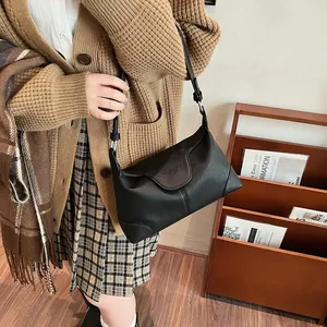 Détail du sac porté épaule en cuir noir avec texture grainée et boucle réglable