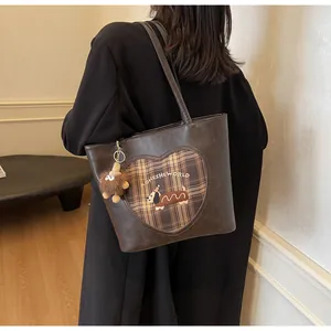 Detail der braunen Vintage-Tasche mit Herzmuster, Dackel-Stickerei und Bommel-Anhänger