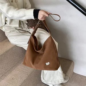 Close-up of brown suede tote bag with metallic pebble buckle and adjustable strap