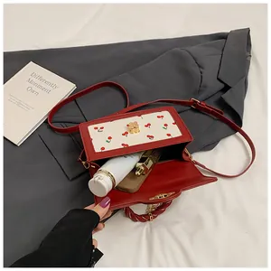 Top view of red cherry pattern handbag showing interior space with lipstick and phone