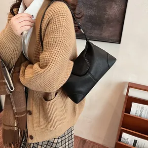 Détail du sac bandoulière en cuir grainé noir avec rabat arrondi et anneaux argentés