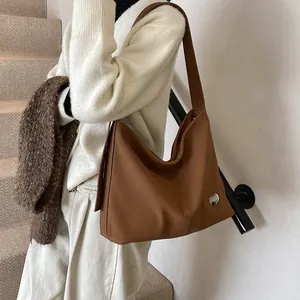 Detail of vintage brown tote bag showing matte texture and silver heart metal ornament