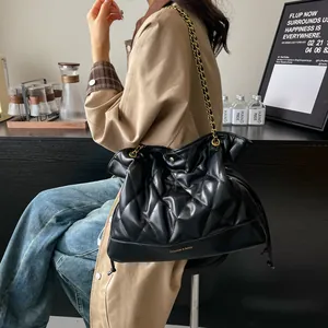 Close-up of black quilted shoulder bag with gold chain strap and brand lettering detail