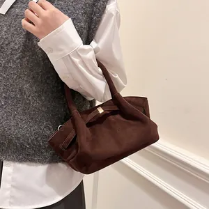 Detail of dark brown suede tote bag featuring premium metal hardware and soft texture