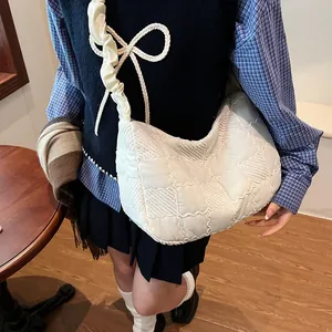 Detail of white quilted nylon dumpling bag with ruffled shoulder strap and puffy texture