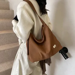 Detail view of large brown faux leather tote bag with a silver heart buckle and stitching