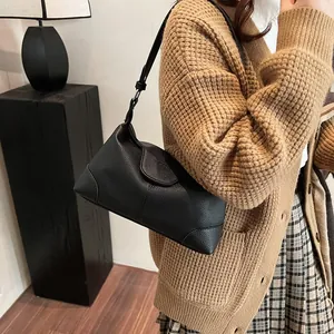 Sac fourre-tout noir minimaliste en cuir texturé litchi porté par un mannequin chic