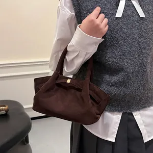 Detail of a dark brown suede tote bag with stylish gold metal buckle and matte texture