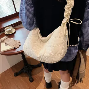 Detail of quilted texture and ruffled bow strap on a beige padded crossbody bag