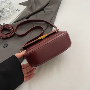 Detailansicht der burgunderroten Ledertasche mit Goldschloss und verstellbarem Gurt