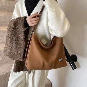 Detail of soft brown suede tote bag with small silver heart charm in casual use