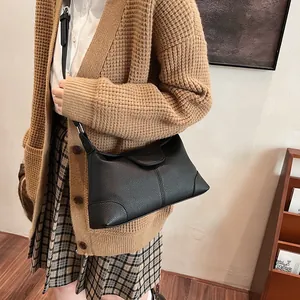 Sac sous le bras noir grainé porté avec un cardigan en tricot pour un look d'automne