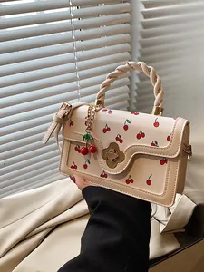 Borsa a tracolla beige chic con stampe ciliegie e chiusura a fiore tenuta da modella