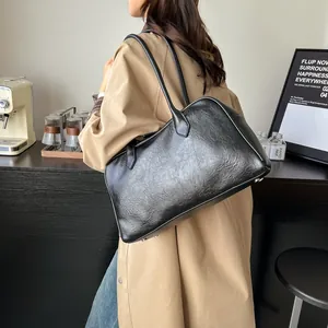 Black vintage wrinkled tote bag with long straps shown from a side view on a model