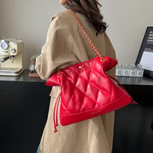 Macro detail of red quilted leather tote with chain strap and drawstring closure